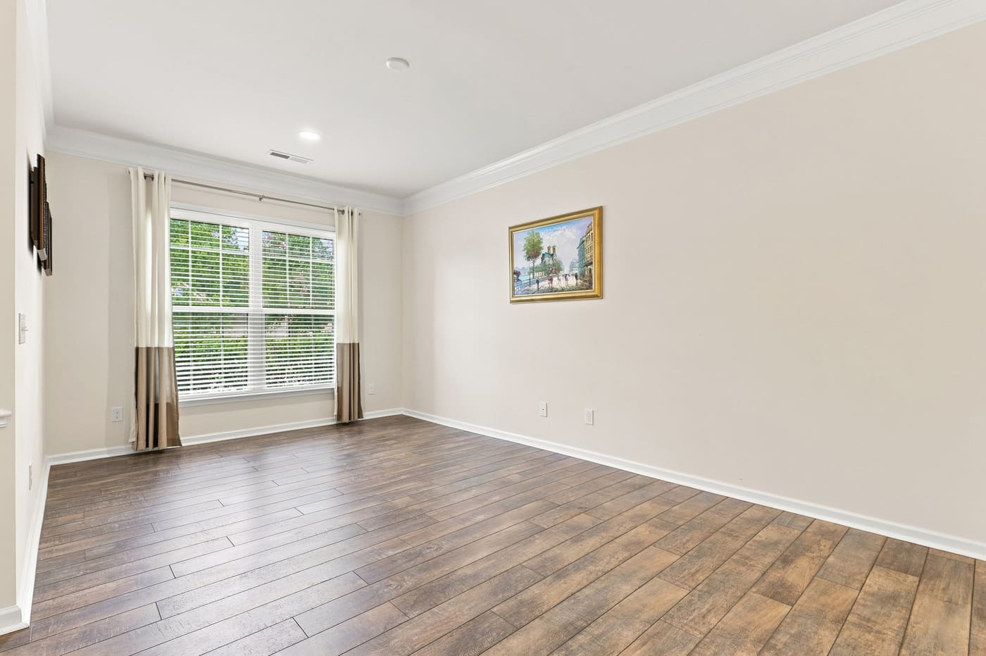 The flex room as it stands today: empty, wood-look flooring, a window to the front yard.
