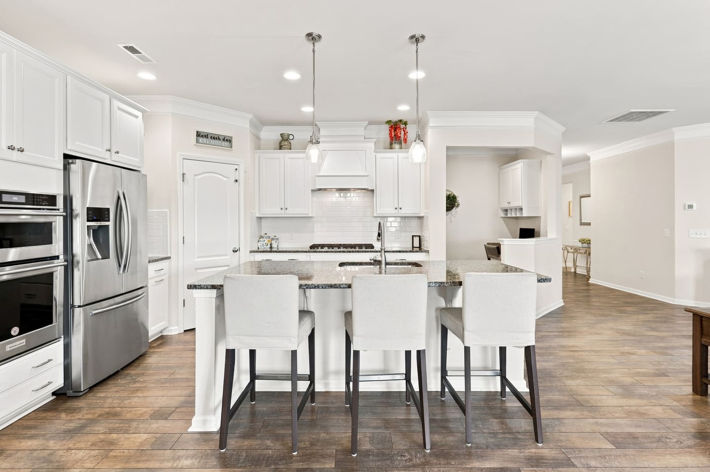 The kitchen island with seating for four, pendant lights above, white cabinetry behind.